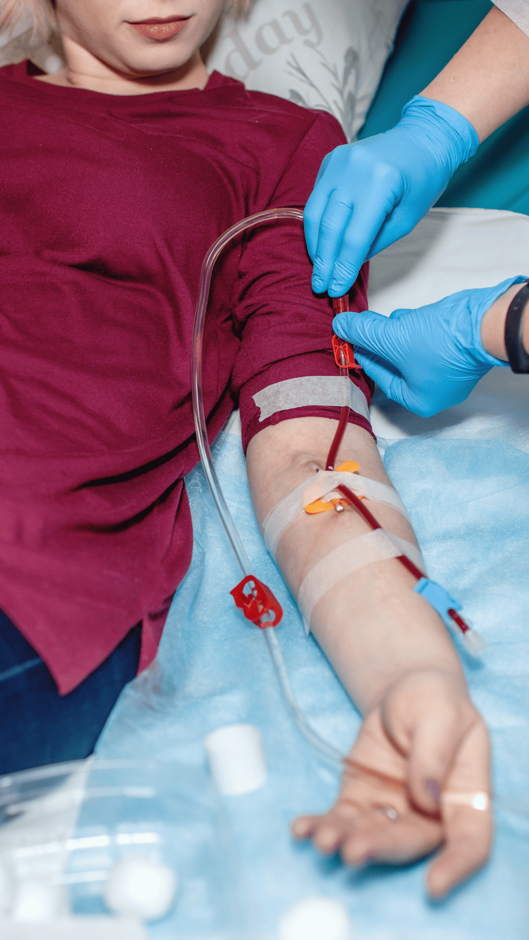 A woman in a hospital bed connected to a blood bag, showing her receiving medical treatment.